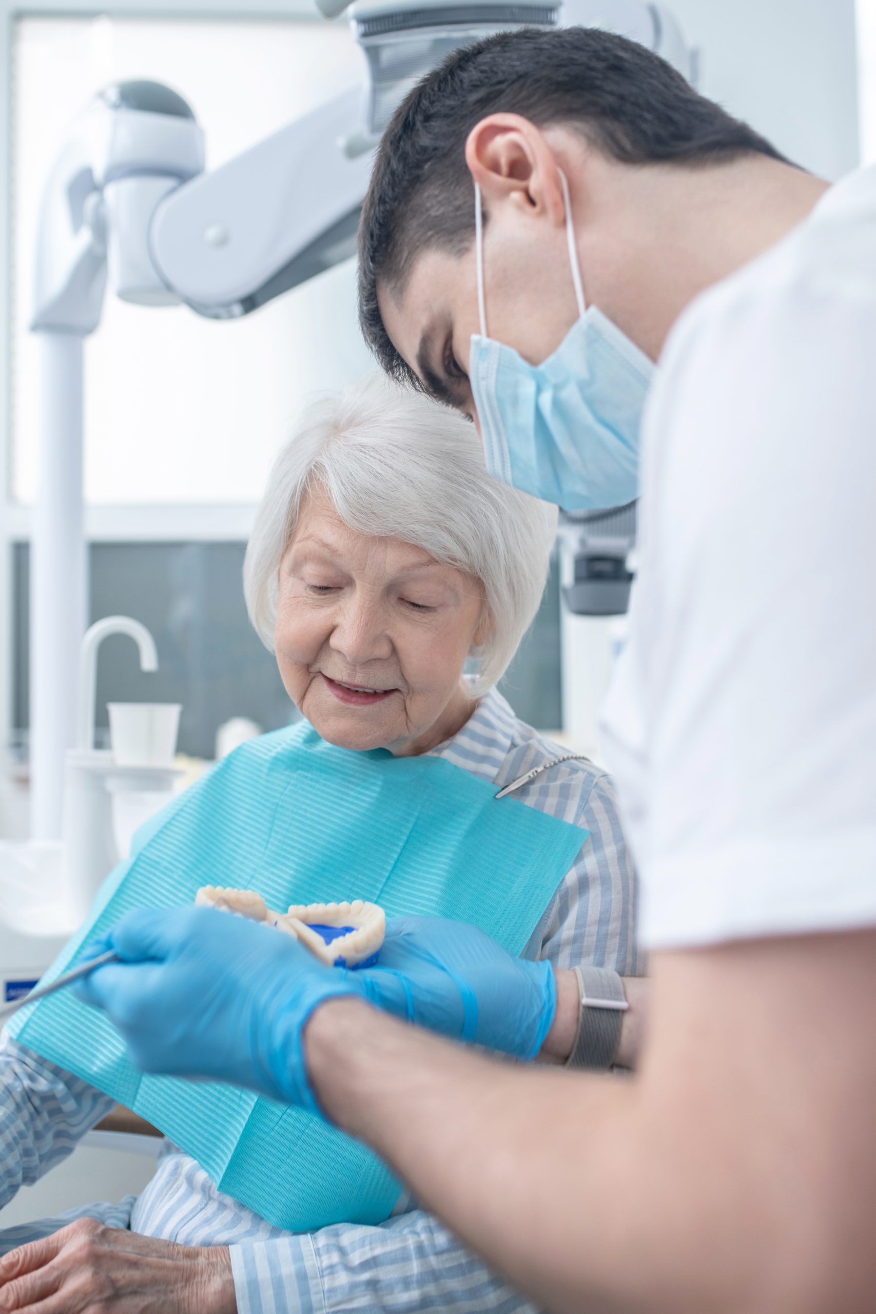 male dental surgeon showing the denture to his npatient