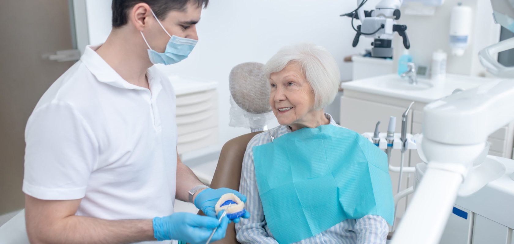 male dentist talking to his senipr patient and explaining her diagnosis